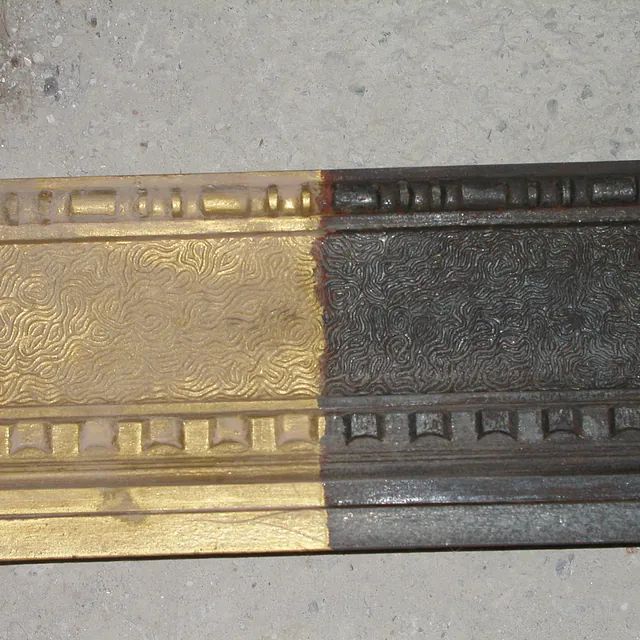 Eine Nahaufnahme einer Messing- und Schwarzleiste auf einer Betonoberfläche.