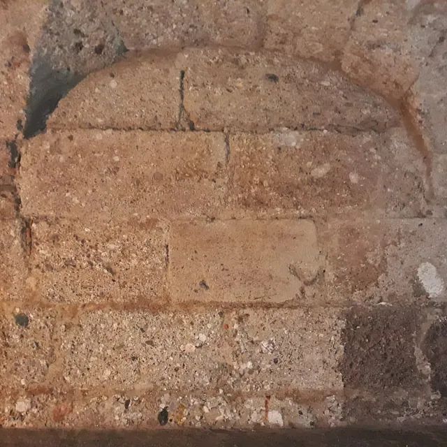 Eine Nahaufnahme einer Ziegelmauer mit einem Loch darin.