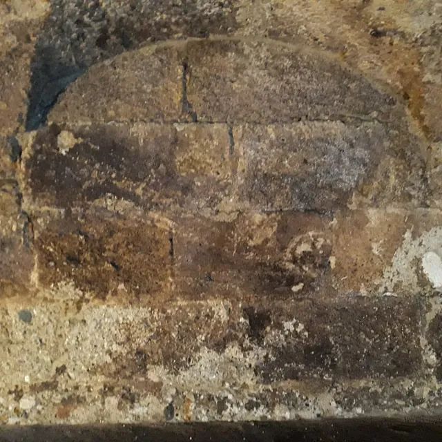 Eine Nahaufnahme einer Ziegelmauer mit einem Loch darin.