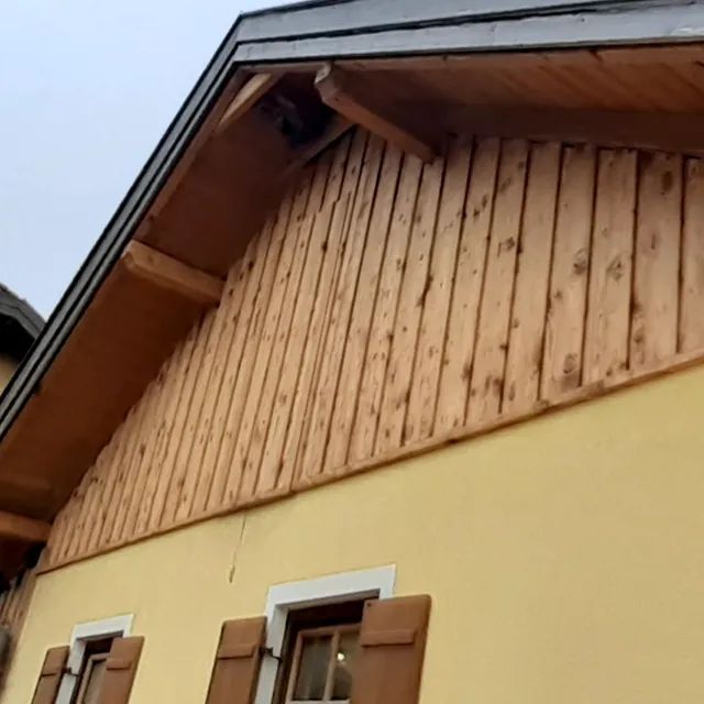 Ein gelbes Haus mit Holzverkleidung und Fensterläden