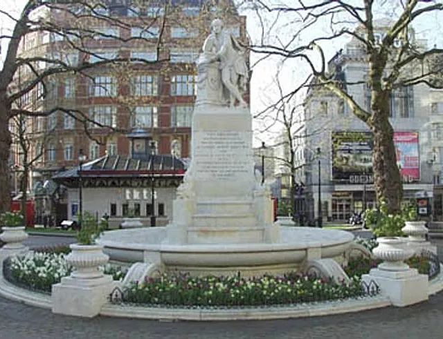Eine Statue in einem Park mit einem Gebäude im Hintergrund