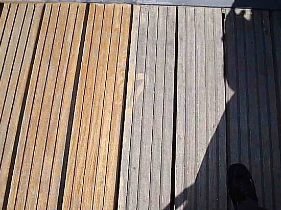 Ein Holzdeck mit dem Schatten einer Person darauf.