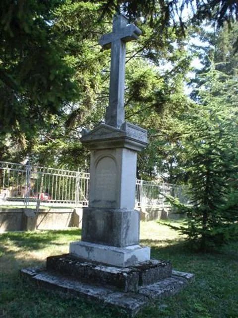 Eine Statue mit einem Kreuz darauf in einem Park