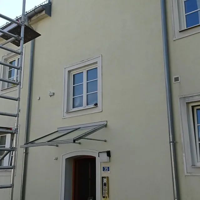 Ein weißes Gebäude mit einem Vordach über der Tür und den Fenstern.