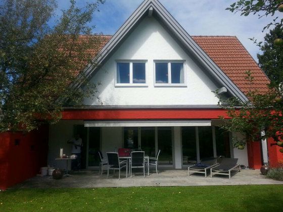 Ein weißes Haus mit rotem Dach und einer Terrasse