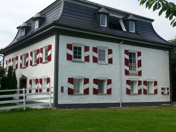 Ein weißes Haus mit roten und weißen Fensterläden