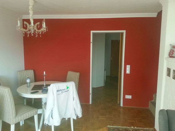 Ein Esszimmer mit roten Wänden und einem weißen Tisch und Stühlen