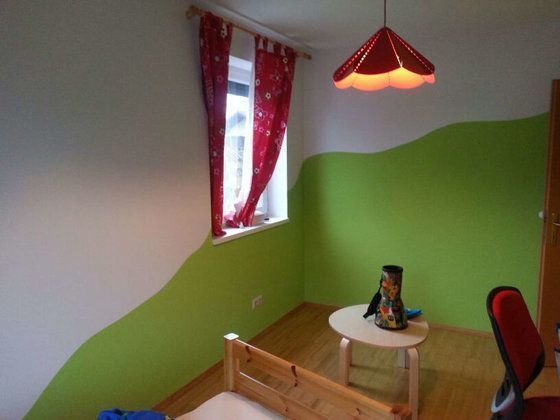 Ein Schlafzimmer mit grünen und weißen Wänden und einer roten Lampe