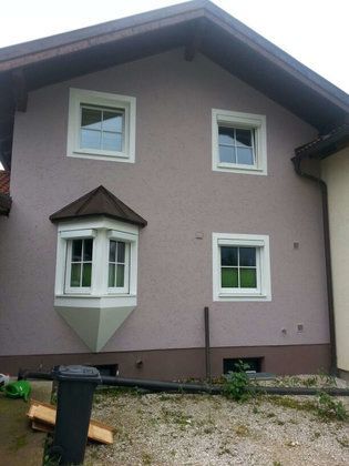 Ein lila Haus mit einer schwarzen Mülltonne davor