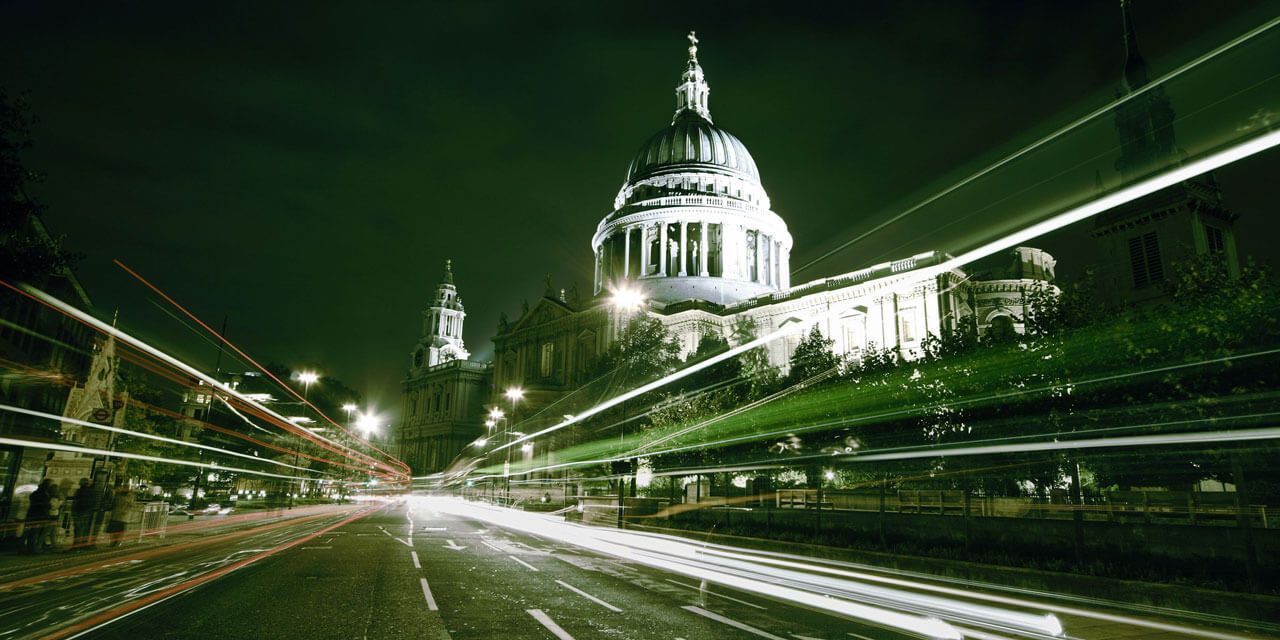 Nachtaufnahme der St. Paul’s Cathedral in London mit Lichtstreifen vorbeifahrender Fahrzeuge.