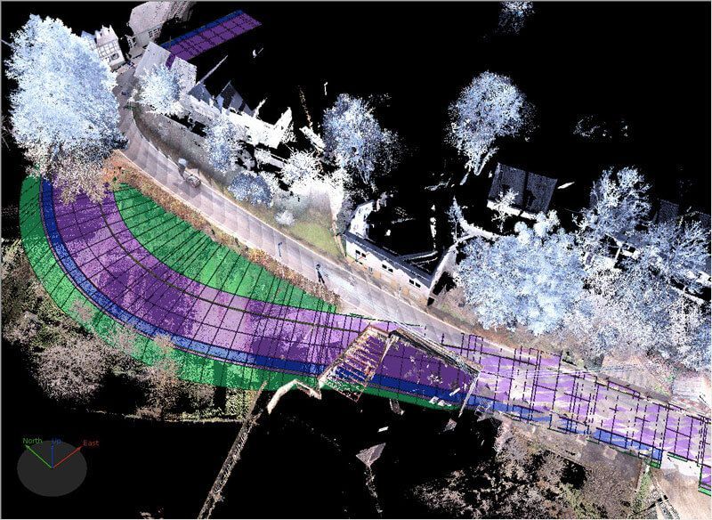 Draufsicht einer Straße mit farbigen Überlagerungen (lila, grün, blau). Punktwolkendaten zeigen umliegende Gebäude und Bäume.