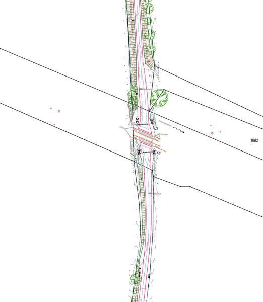 Draufsicht auf eine Straße mit Brücke und Stromleitungen. Grüne, rote und schwarze Linien zeigen den Straßenverlauf und die umgebende Vegetation.