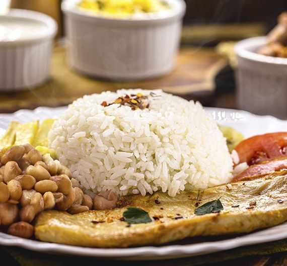 Un plato de comida con arroz, frijoles y carne en una mesa.