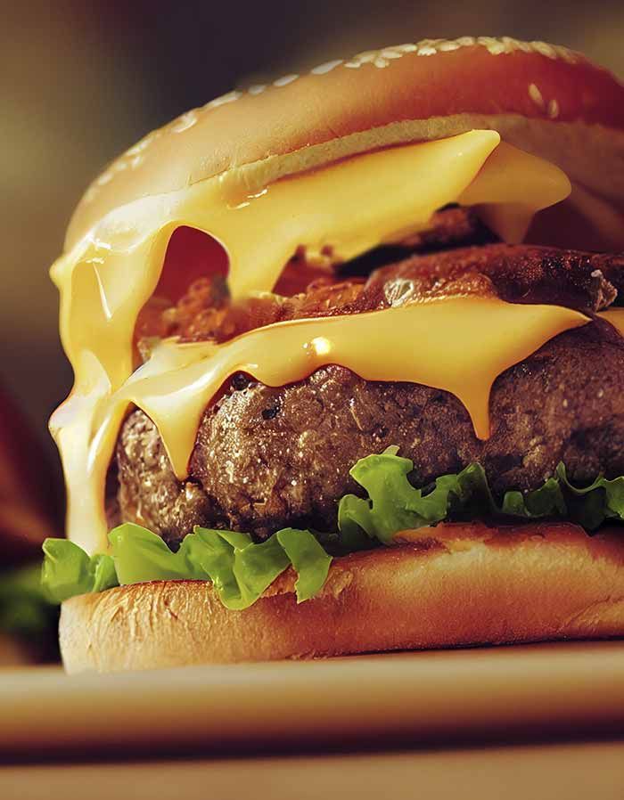 Un primer plano de una hamburguesa con queso y lechuga en un pan.