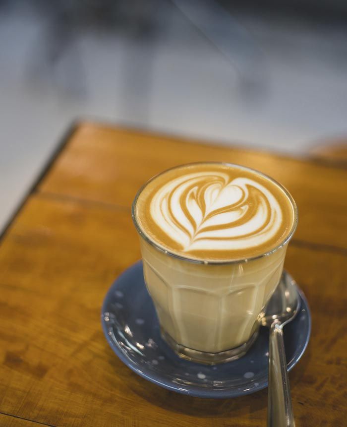 Una taza de capuchino en un platillo con una cuchara.
