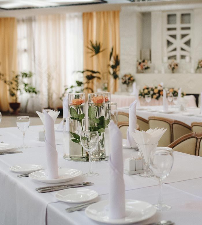 Una mesa con platos, vasos, servilletas y flores sobre ella.