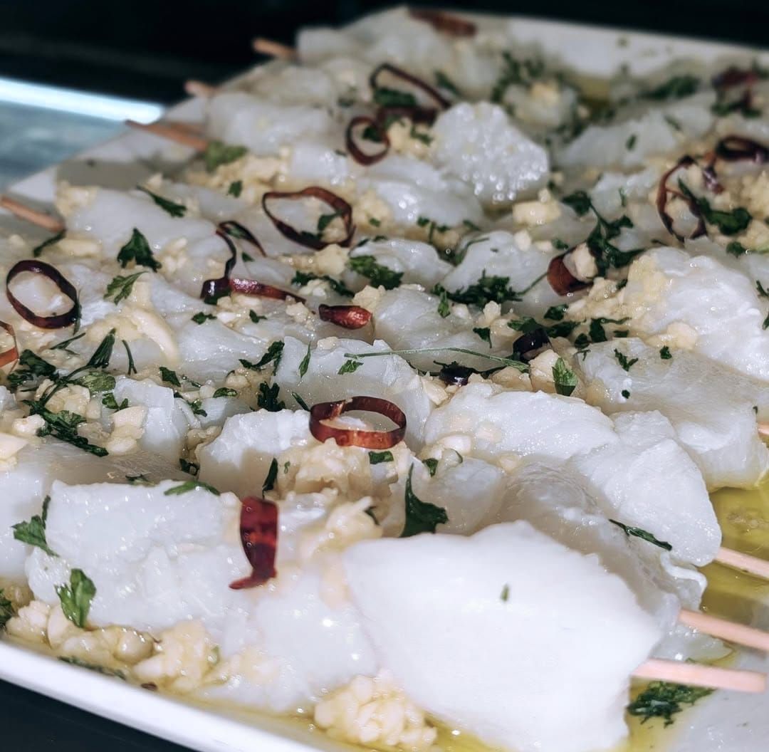 Vieiras crudas en brocheta con ajo, perejil y hojuelas de chile rojo.