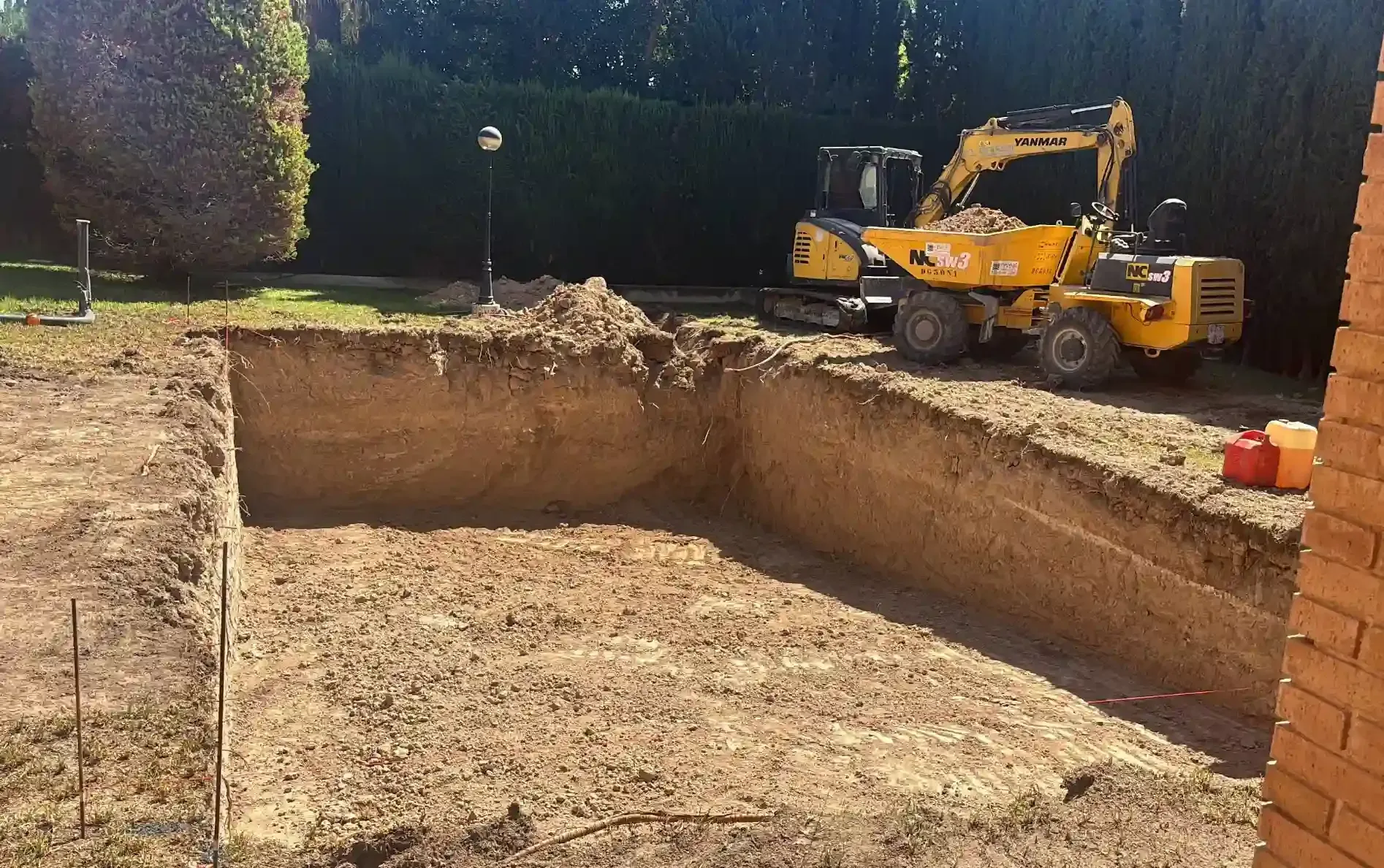 Excavadora amarilla demoliendo una estructura de hormigón en un entorno al aire libre, con un operador visible.