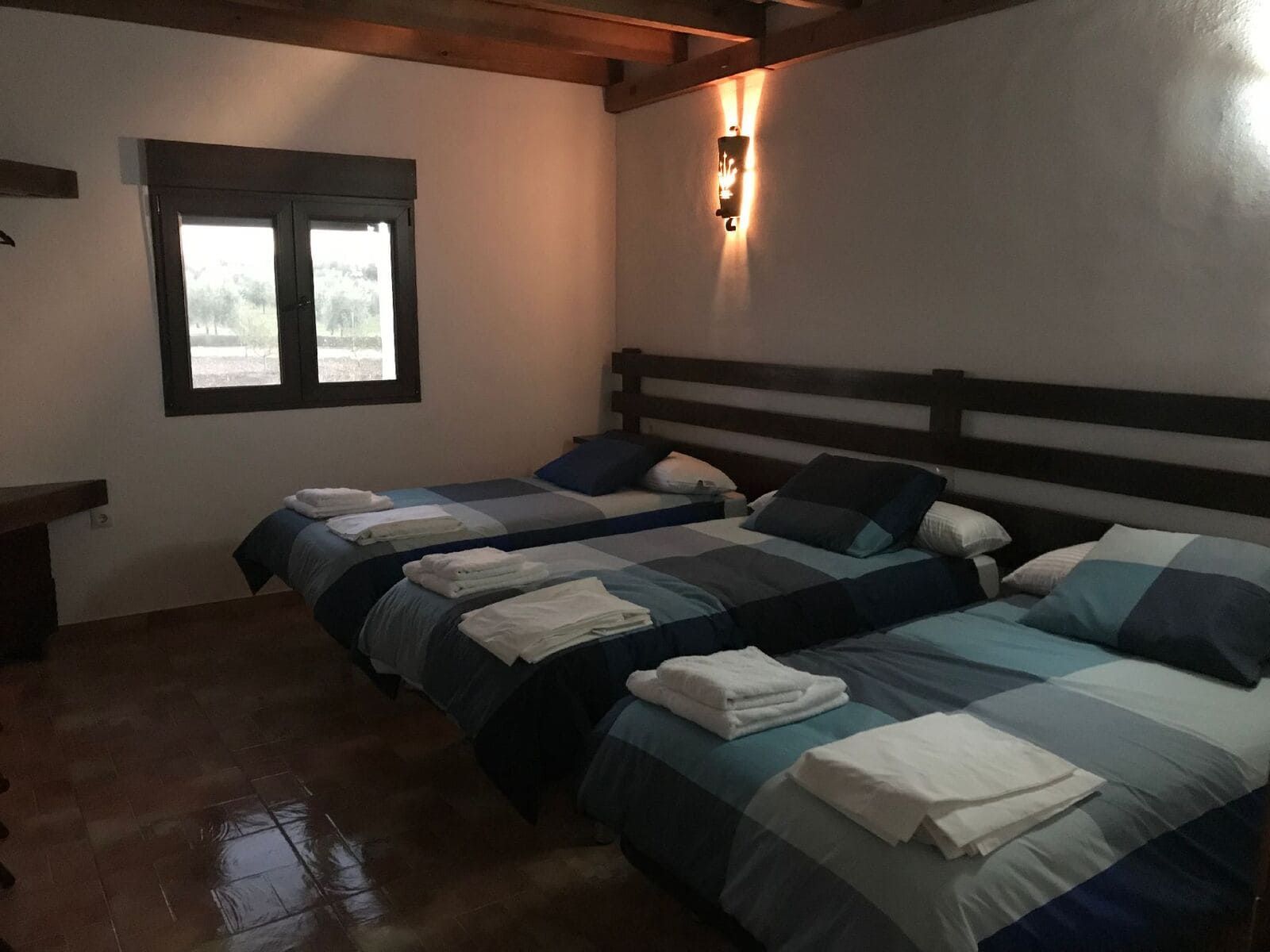 Un dormitorio con tres camas, cada una con mantas a cuadros azules y toallas blancas.