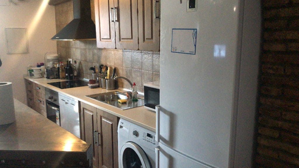 Cocina con gabinetes, electrodomésticos, estufa, fregadero y refrigerador. Predominan los tonos marrón y beige.