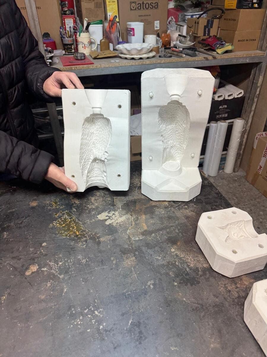 Una persona sostiene dos moldes de arcilla sobre una mesa.