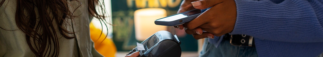 Persona sosteniendo un escáner, cerca de otra persona de cabello oscuro. Fondo borroso.