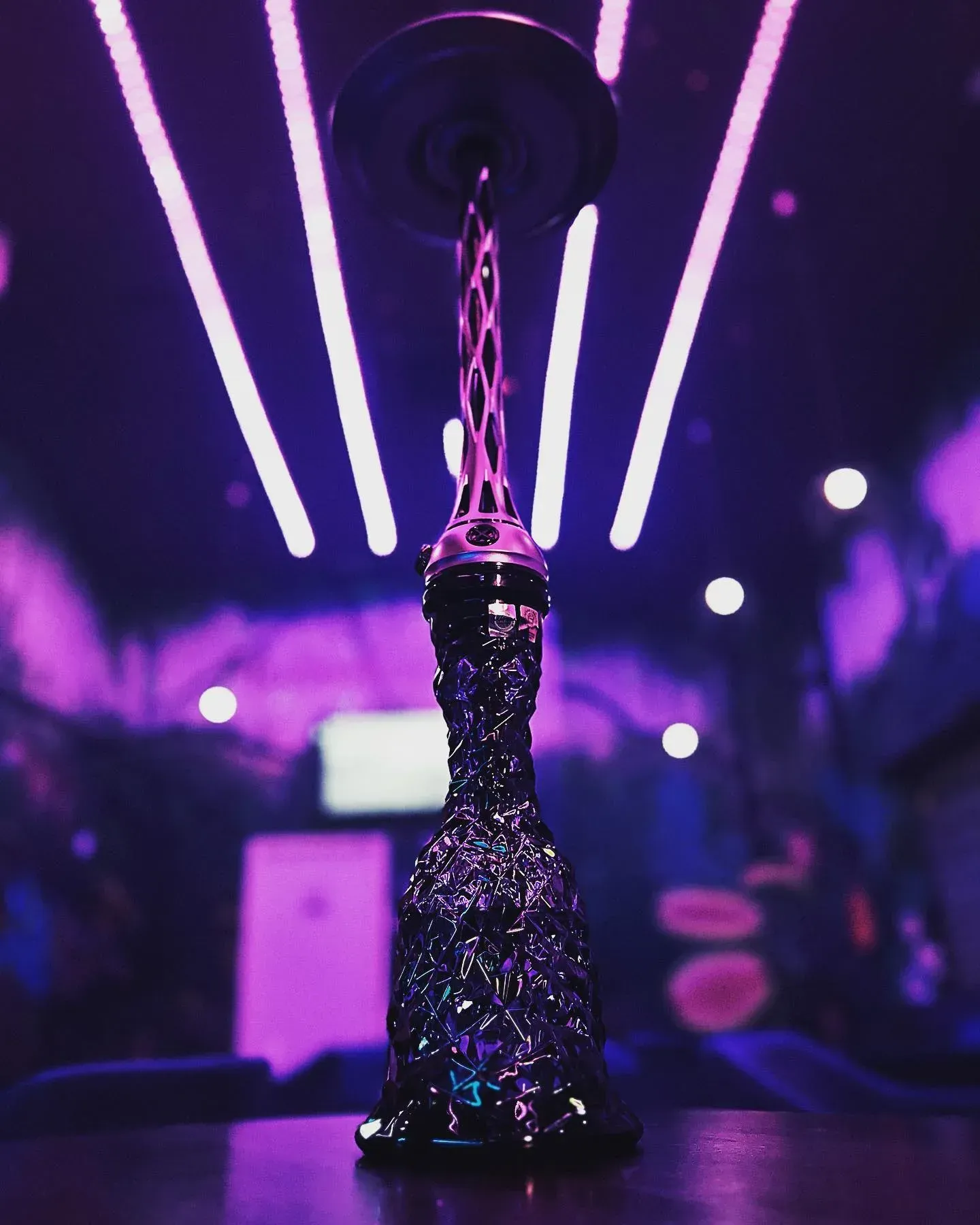 Cachimba morada sobre una mesa, con iluminación de neón violeta en una habitación poco iluminada.