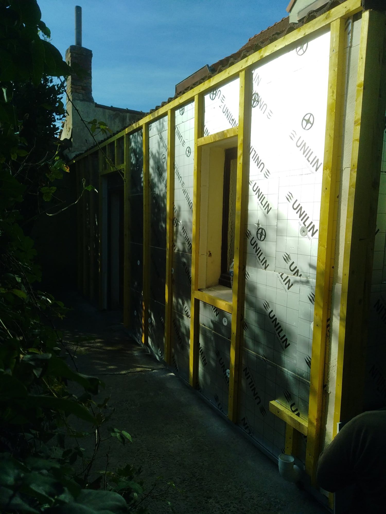 Ossature du mur extérieur avec isolation, une ouverture de fenêtre et un chemin sombre.