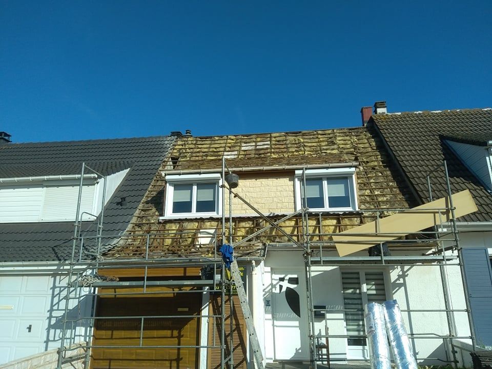 Toiture de maison partiellement en construction ; ouvrier sur échafaudage ; ciel bleu.