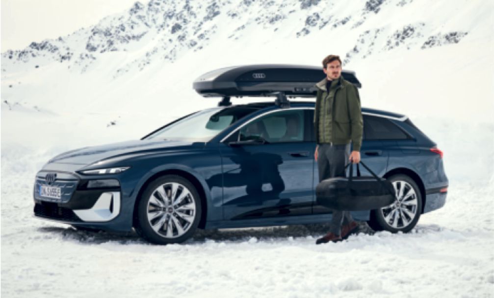 Blaues Auto im Schnee mit einem Mann stehend davor
