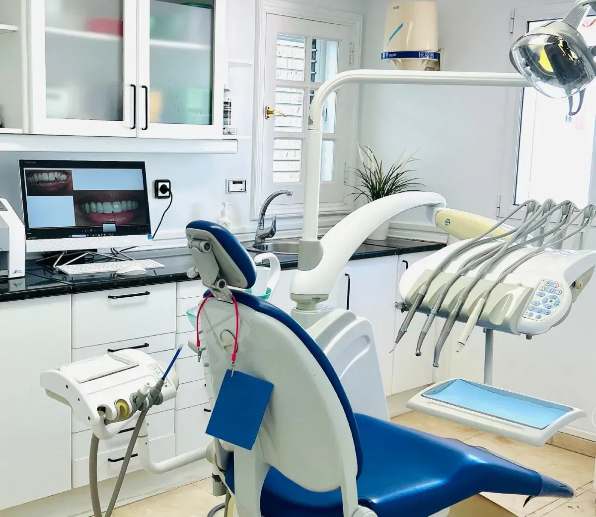 Una luminosa sala de exploración dental con un sillón para el paciente de color azul y blanco, instrumental dental