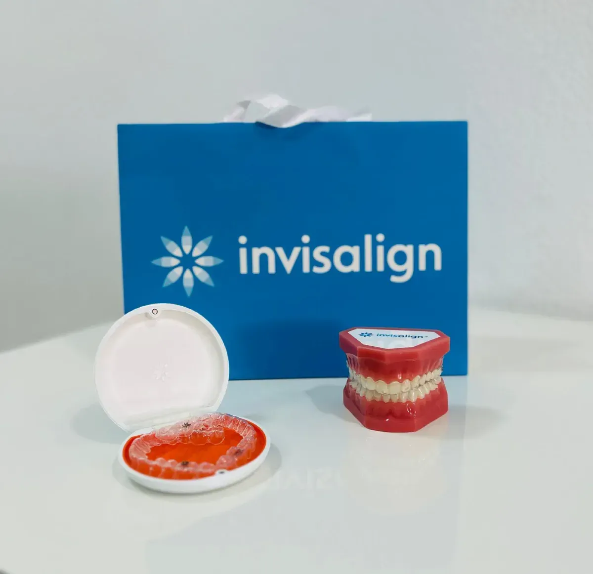 Una bolsa con el logotipo de Invisalign, un modelo dental con alineadores y un solo alineador