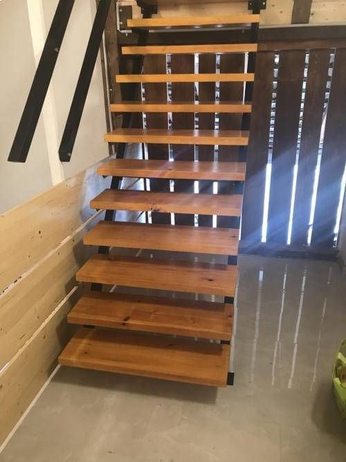 Schwebende Holztreppe mit schwarzen Metallstützen in einem modernen Interieur