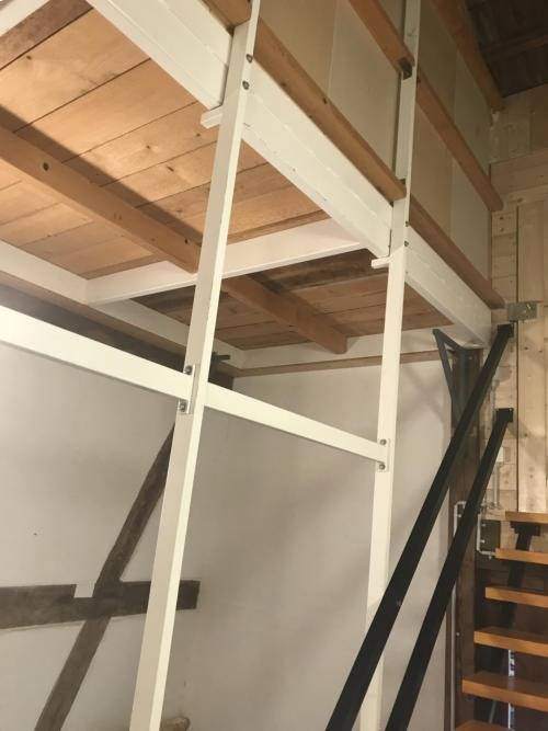 Hochbettgestell und Holztreppe in einem kleinen Zimmer mit Dachschräge