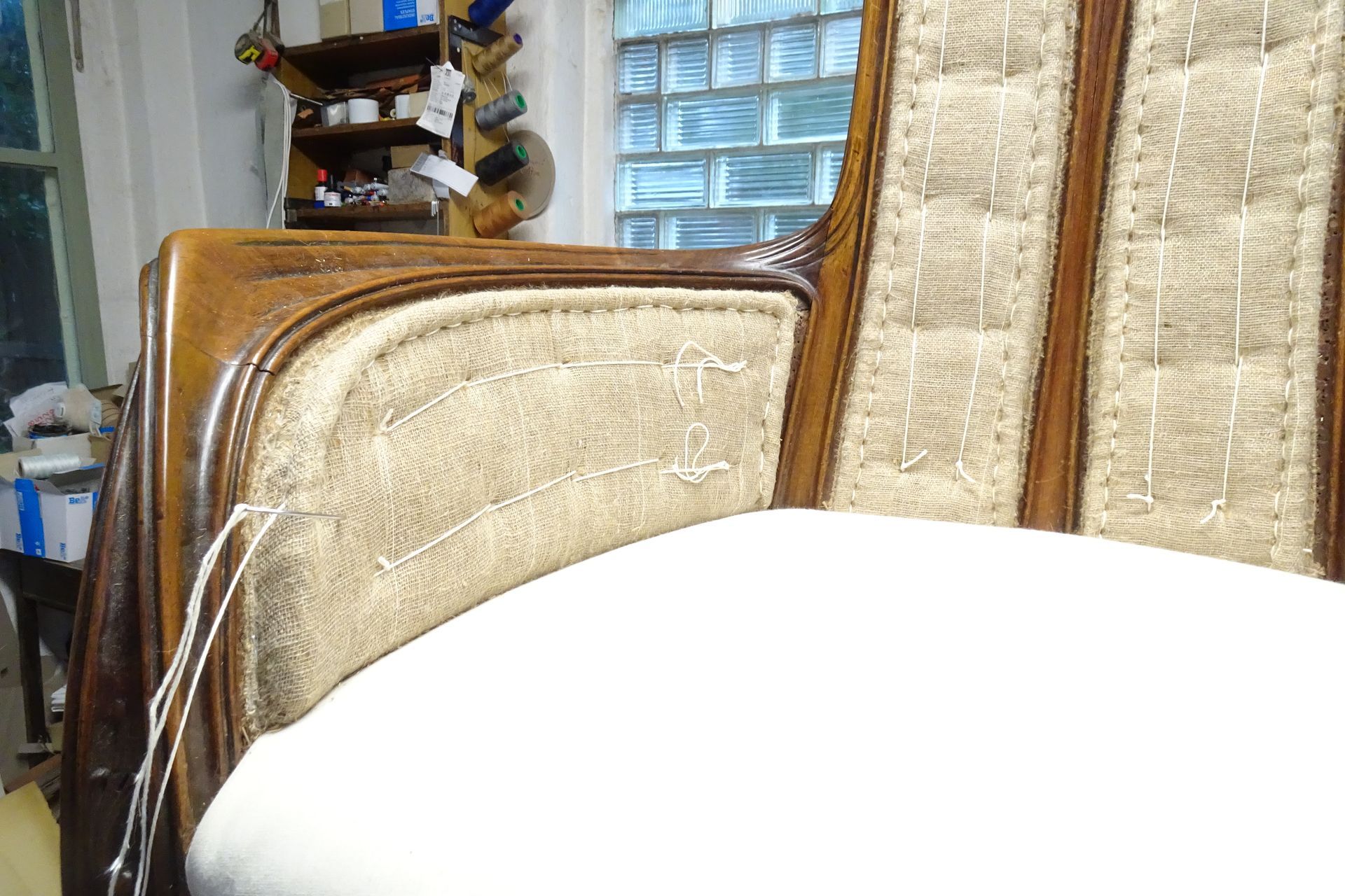 Ein beigefarbener Polstersessel neben einem hellen Fenster, im Vordergrund ein weißer runder Tisch.