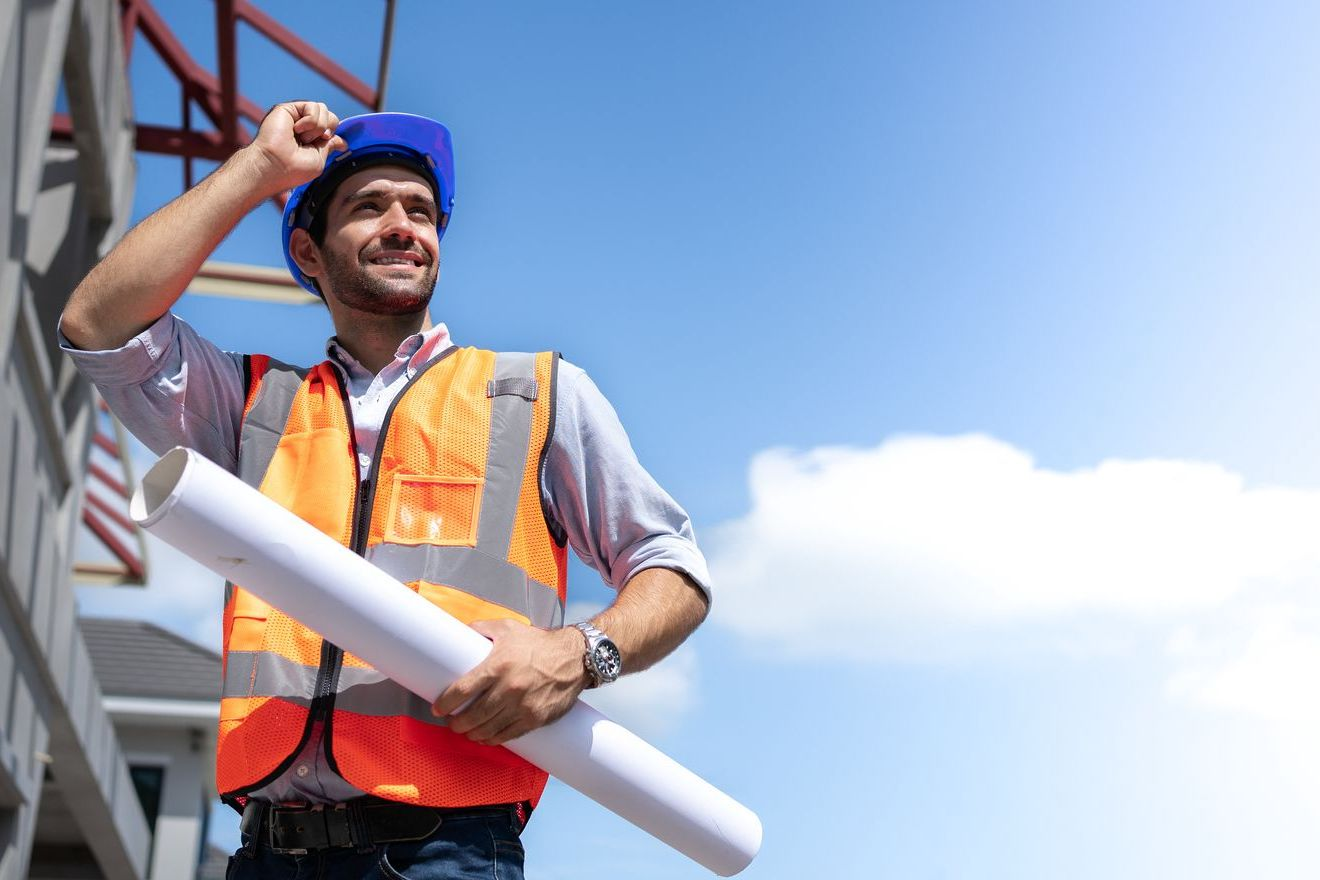 Ein Bauarbeiter trägt einen blauen Helm und eine orangefarbene Schutzweste Ein Bauarbeiter trägt einen blauen Helm und eine orangefarbene Schutzweste