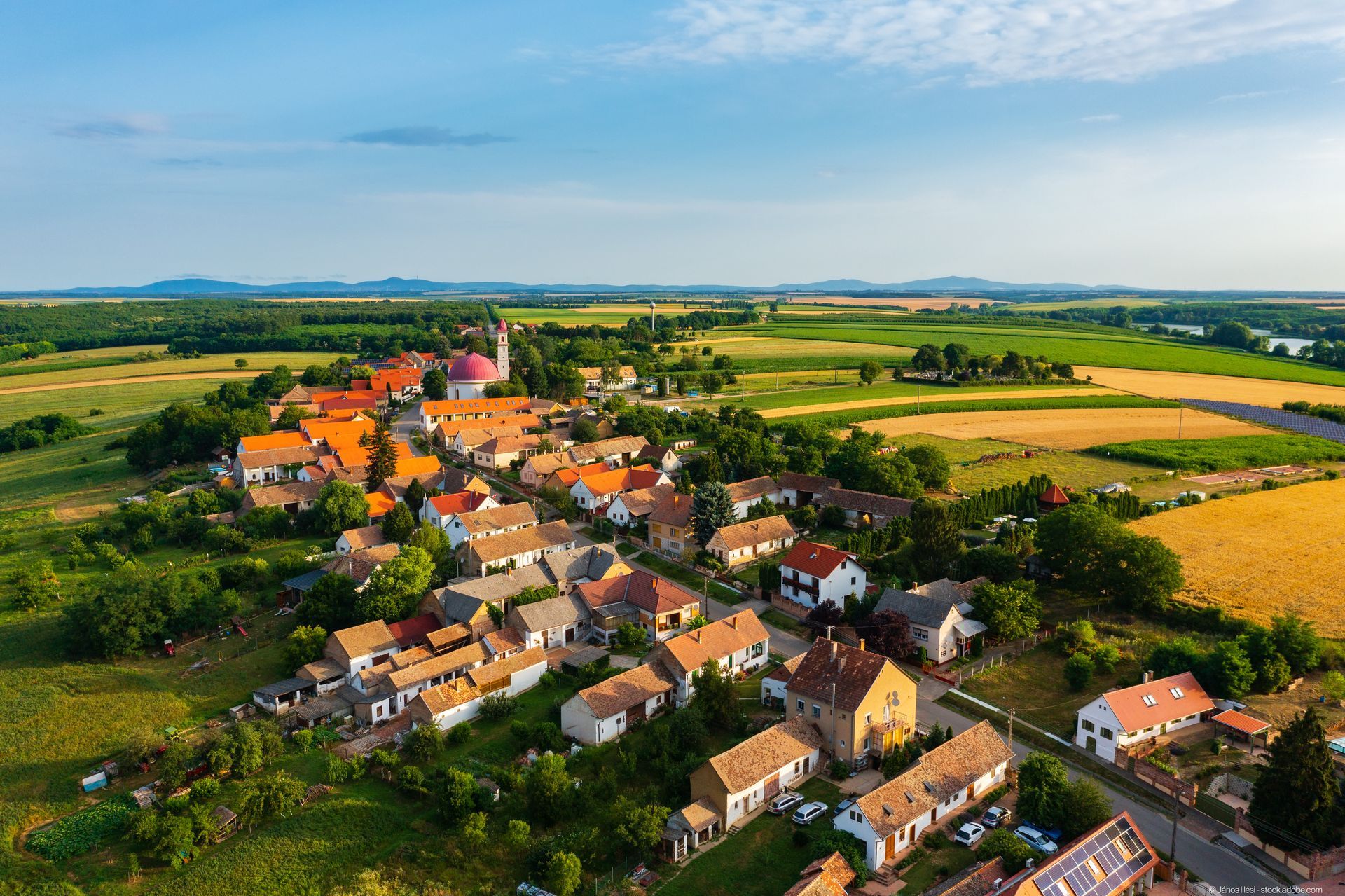 Eine Luftaufnahme eines kleinen Dorfes mit vielen Häusern und Feldern Eine Luftaufnahme eines kleinen Dorfes mit vielen Häusern und Feldern