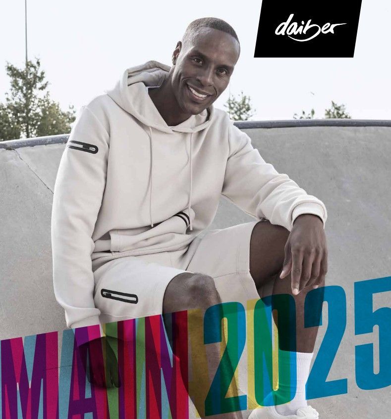 Un homme en sweat-shirt beige et short sourit, assis dans un skatepark. Logo Daiber en haut à droite, « MAIN 2025 » en caractères colorés.