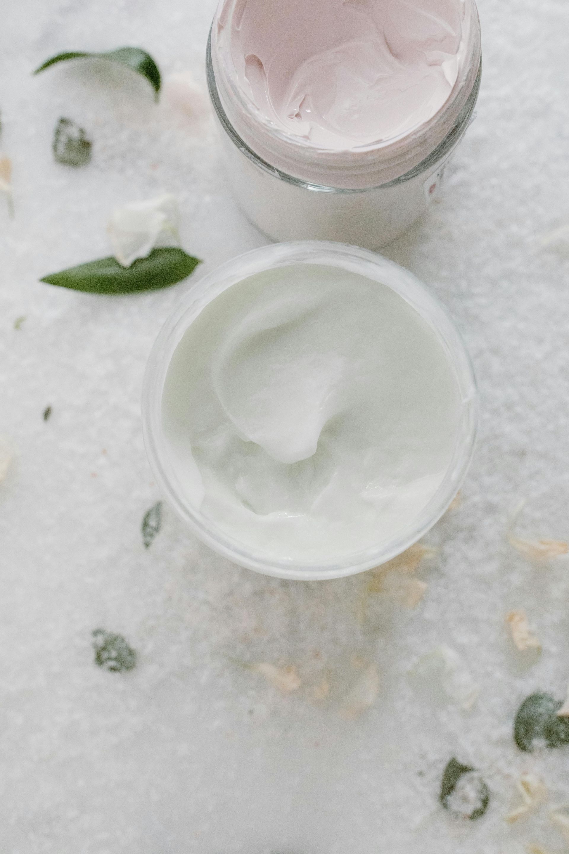Dos tarros de crema, uno rosa pálido y otro blanco,