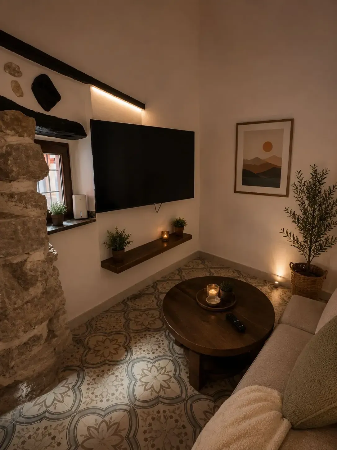 Acogedora sala de estar con azulejos estampados, televisor montado en la pared, mesa de centro iluminada con velas.