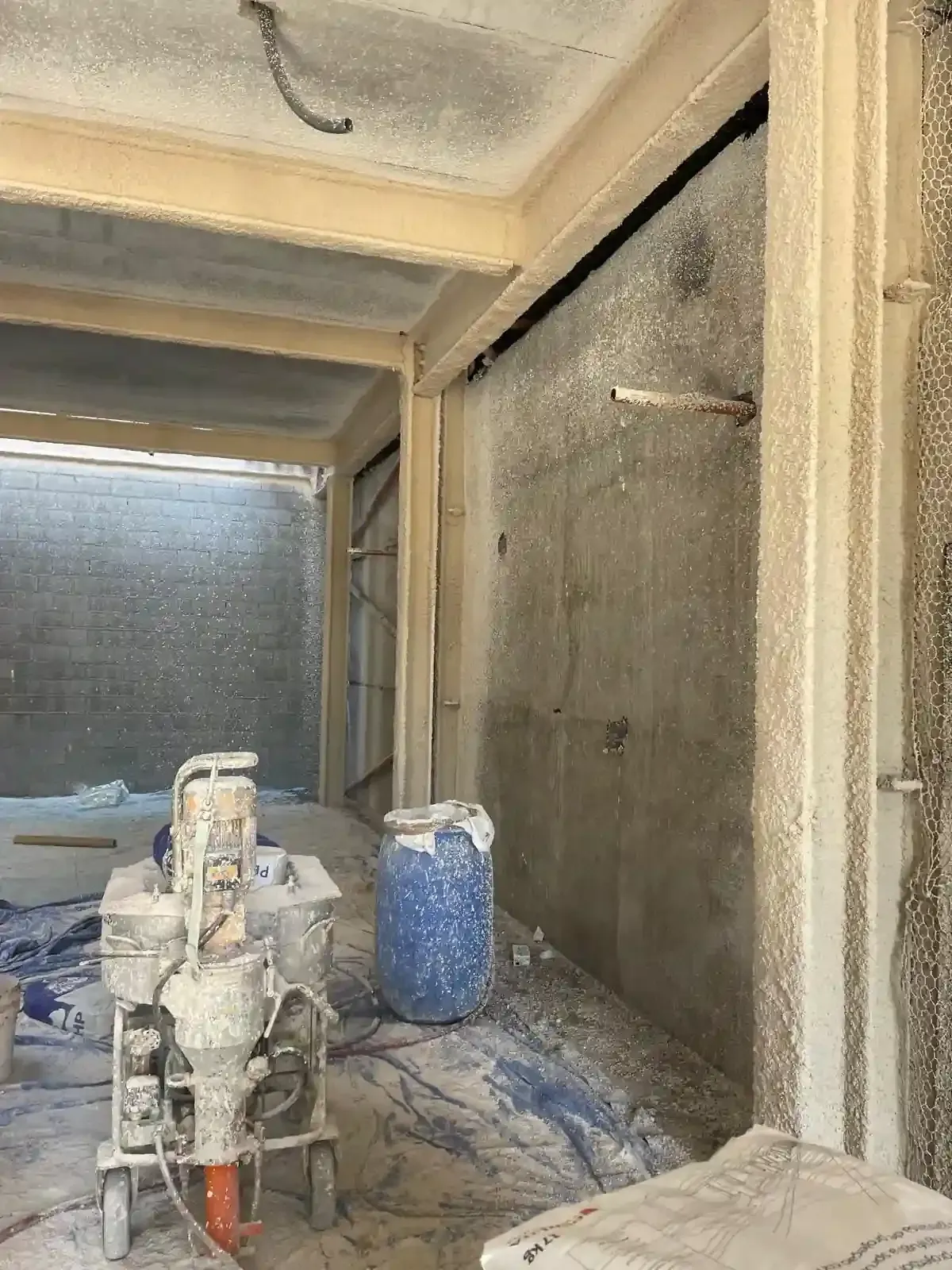 Vista interior de un sitio de construcción con aislamiento en aerosol en las paredes y equipos instalados.