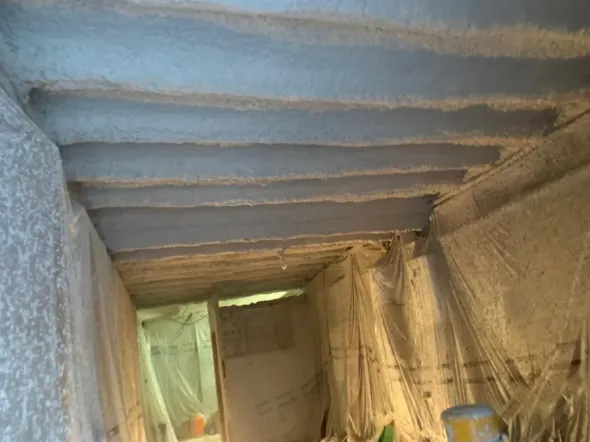 Techo de sótano con aislamiento, vigas y láminas de plástico.