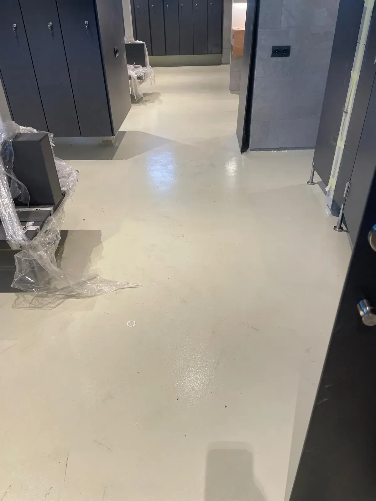 Un vestuario con taquillas grises y suelo de color claro.