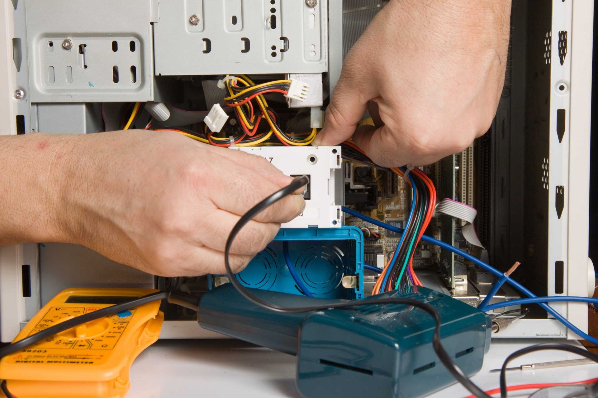 Una persona está trabajando en una computadora con un multímetro.