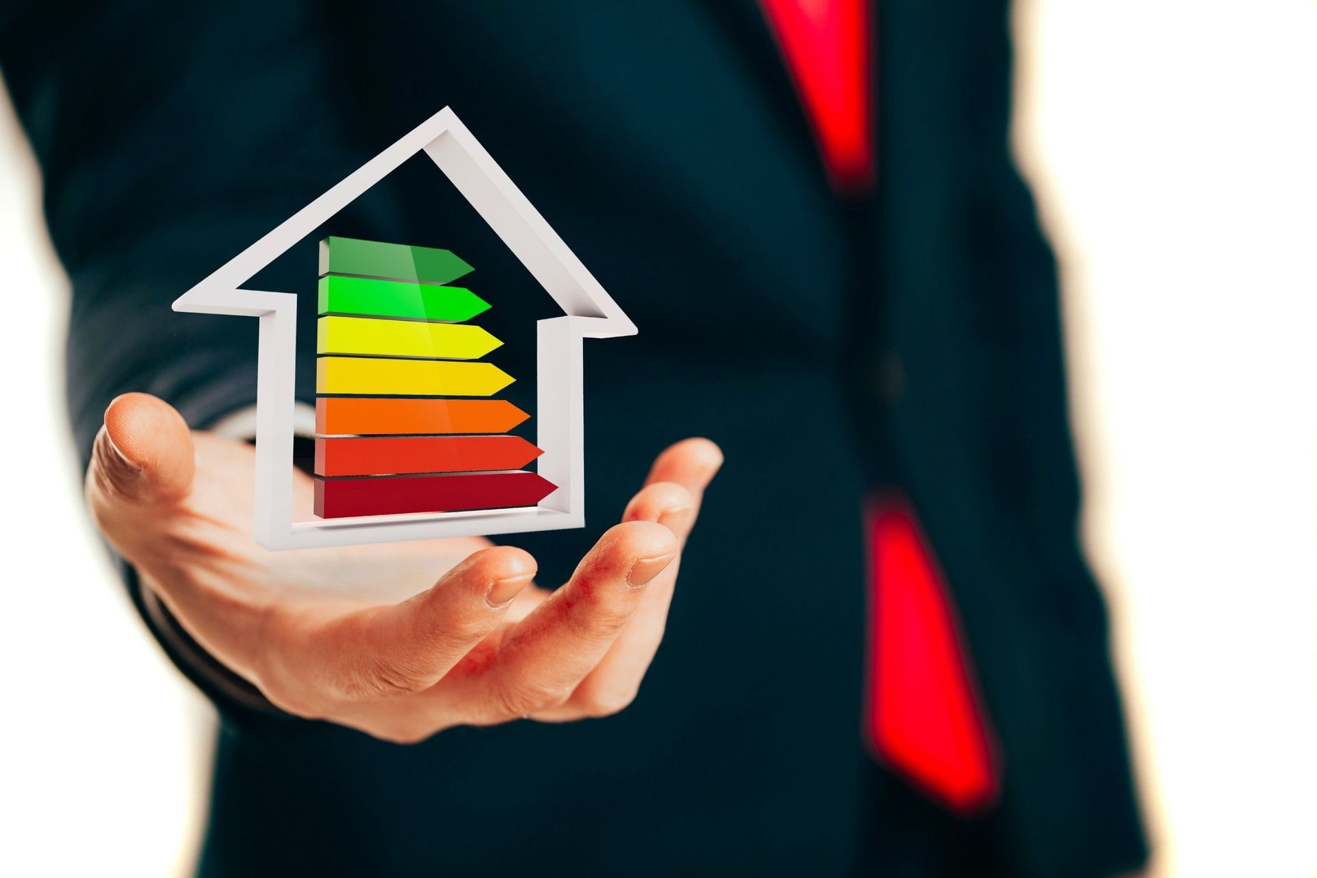 Un hombre con traje y corbata sostiene una casa con clasificaciones energéticas.