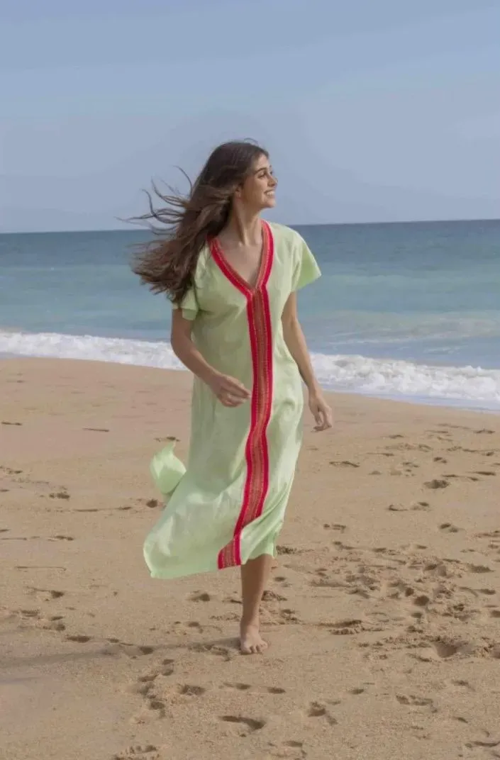 Una mujer vestida de verde corre en una playa de arena cerca del océano.