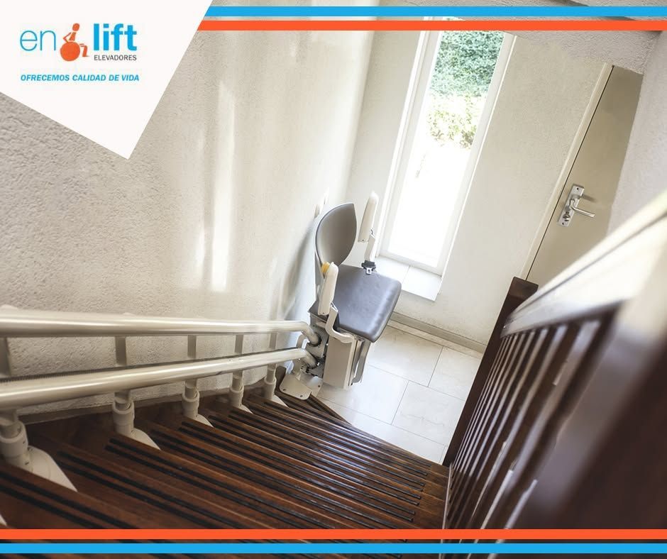 Silla salvaescaleras instalada en una escalera de madera en un luminoso pasillo interior de una vivienda.