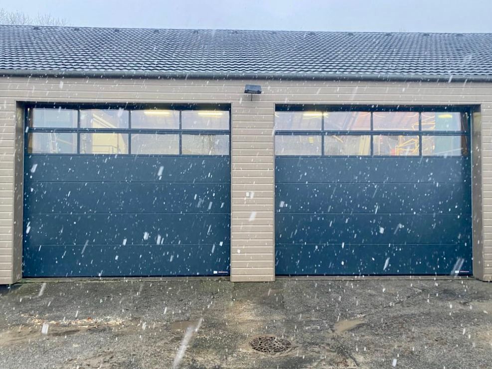 Deux portes de garage bleues sur un bâtiment beige sous la neige