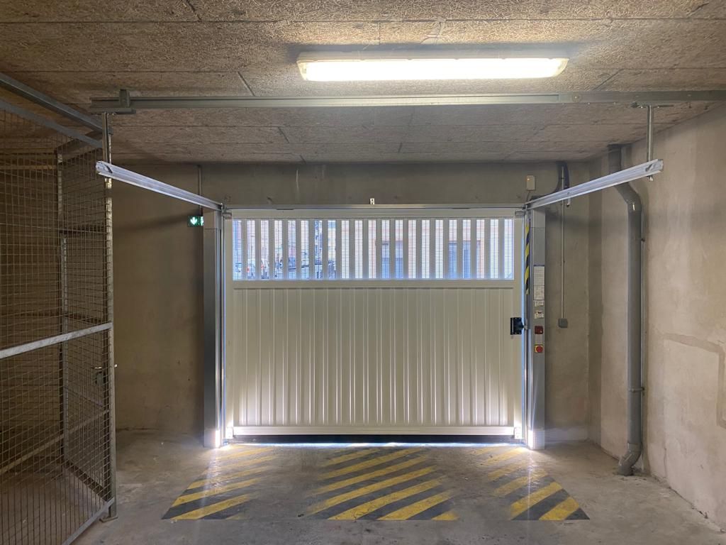Sortie de garage souterrain avec barrière rayée et éclairage puissant au plafond