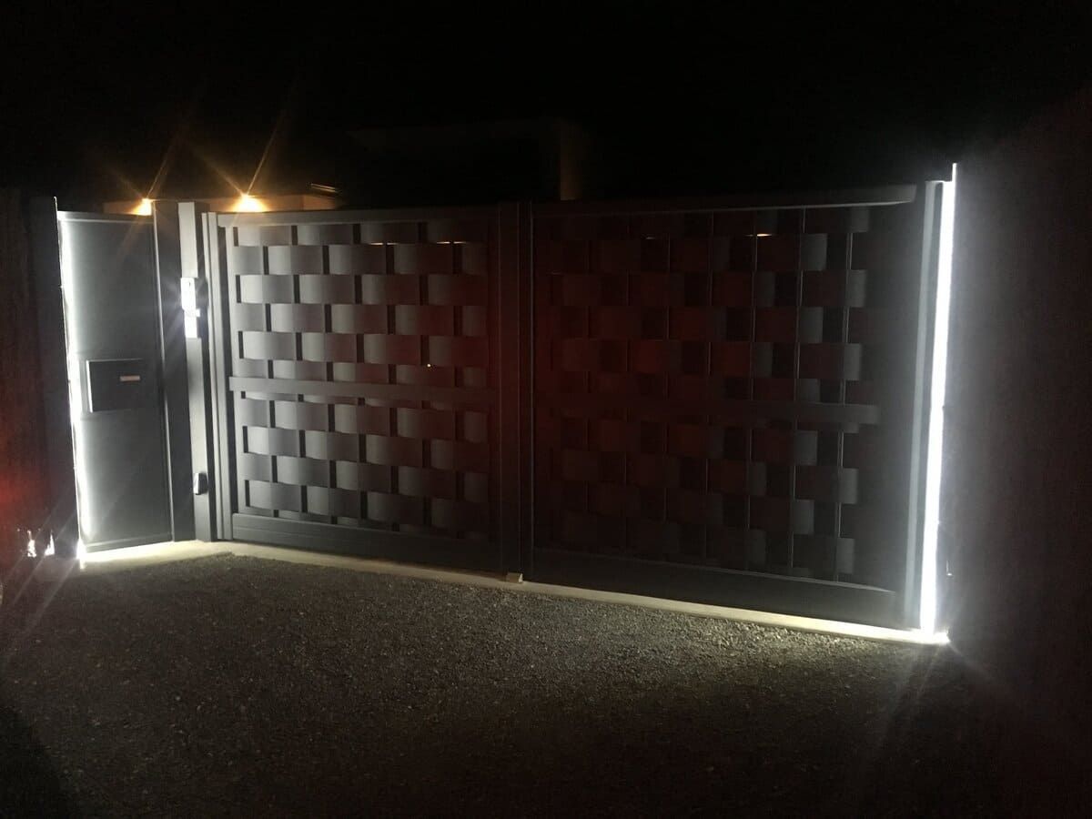 Portail métallique illuminé la nuit avec des lumières verticales brillantes des deux côtés